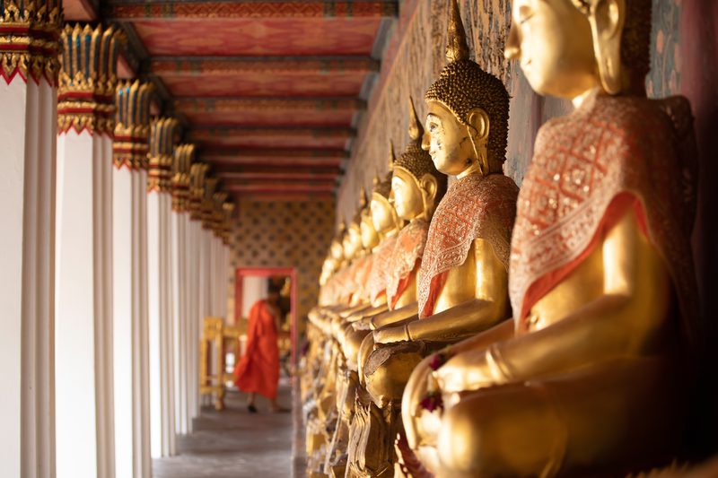 Row of golden Buddha statues inside a Buddhist temple