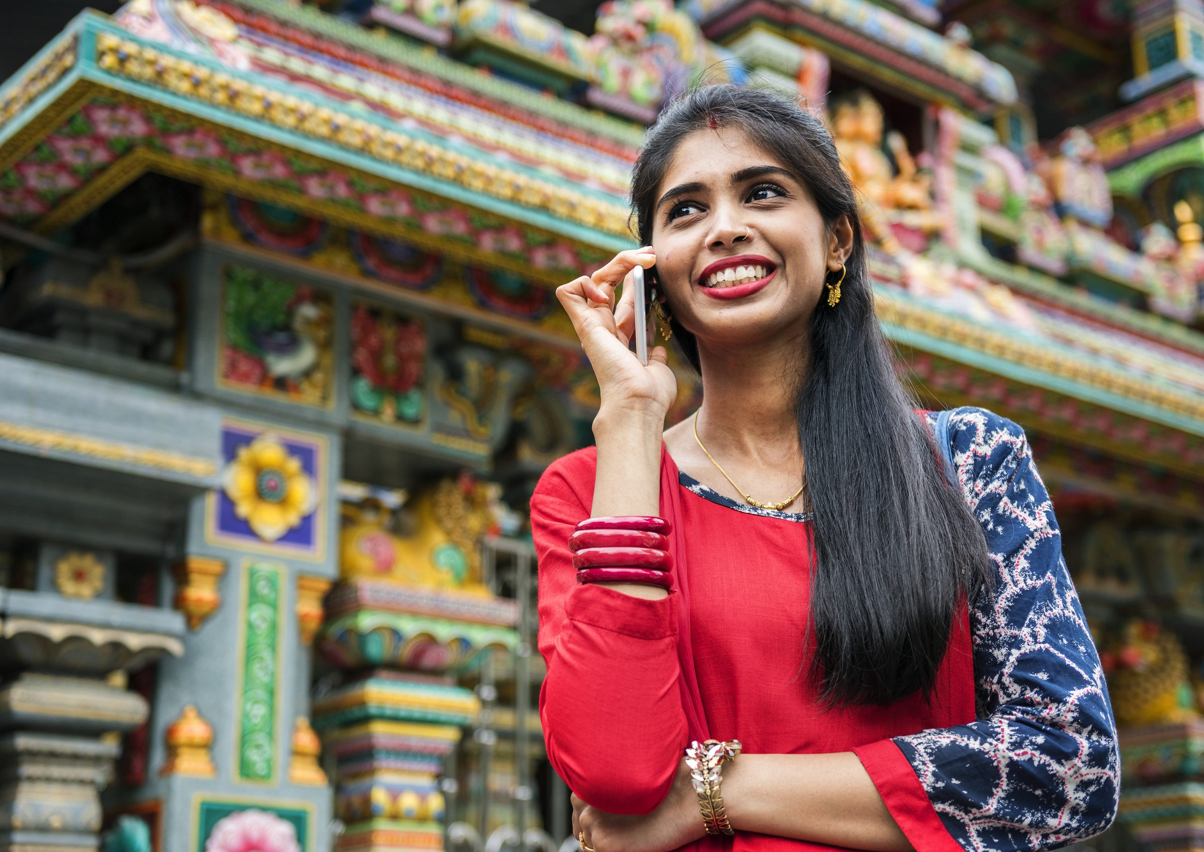Junge Frau im roten Sari vor einem Hindu-Tempel